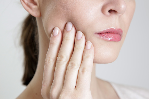 Woman holding her hand to her painful jaw