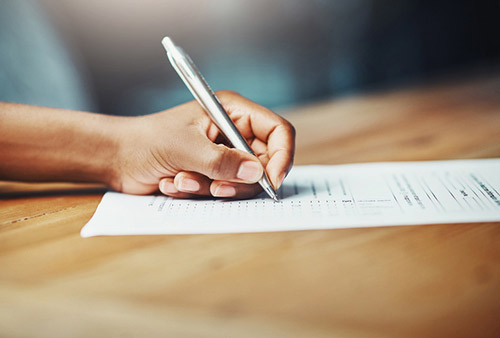 Hand of a person filling out new patient form.